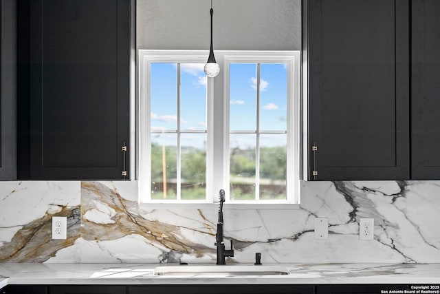 room details with pendant lighting, light countertops, tasteful backsplash, dark cabinets, and a sink