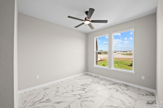 empty room featuring baseboards, ceiling fan, and marble finish floor