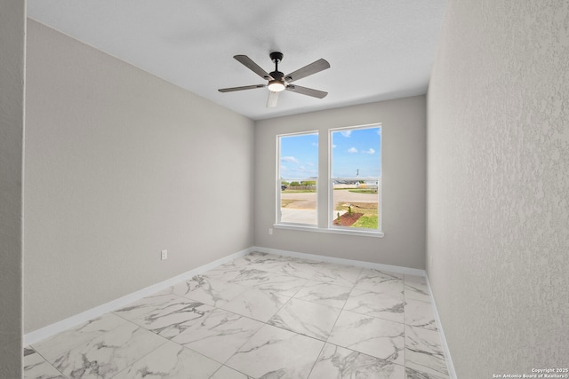 unfurnished room with baseboards, a ceiling fan, and marble finish floor