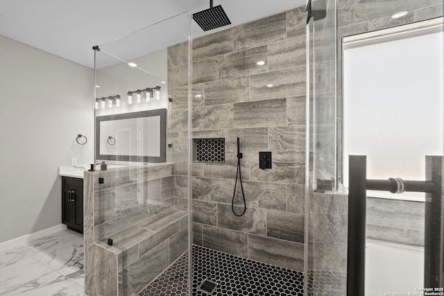 bathroom with vanity, marble finish floor, baseboards, and tiled shower