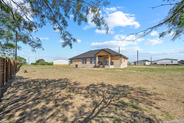 back of property featuring fence and a yard