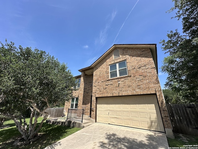 view of front of house featuring brick siding, an attached garage, driveway, and fence