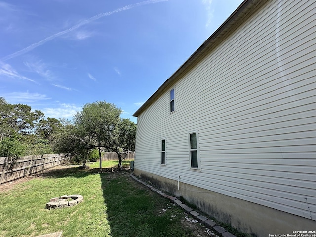 view of home's exterior with a yard, fence, and a fire pit