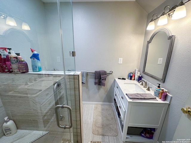 full bathroom featuring baseboards, a shower stall, and vanity