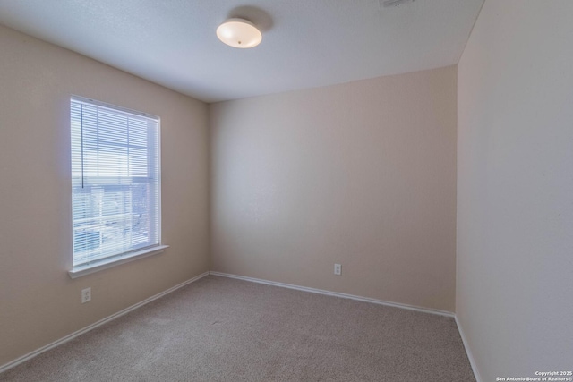 carpeted spare room with plenty of natural light and baseboards