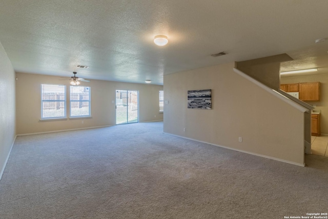 unfurnished living room featuring visible vents, a textured ceiling, ceiling fan, and light carpet