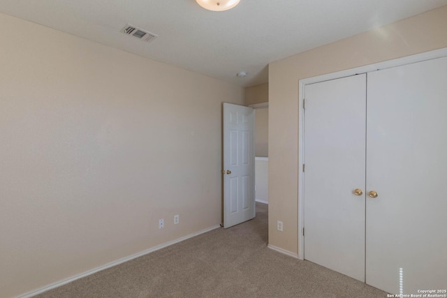 unfurnished bedroom featuring baseboards, light carpet, a closet, and visible vents