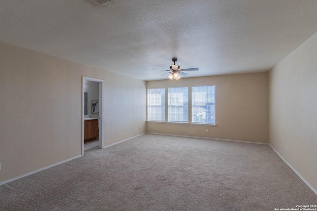 spare room featuring baseboards, ceiling fan, a textured ceiling, and light colored carpet