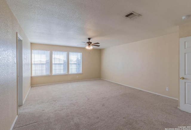 empty room with baseboards, ceiling fan, light carpet, and visible vents