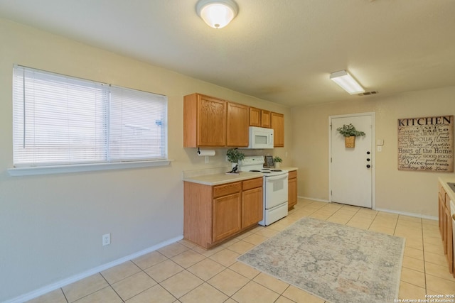 kitchen with light tile patterned flooring, white appliances, light countertops, a healthy amount of sunlight, and visible vents