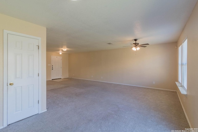 carpeted empty room with a ceiling fan and baseboards