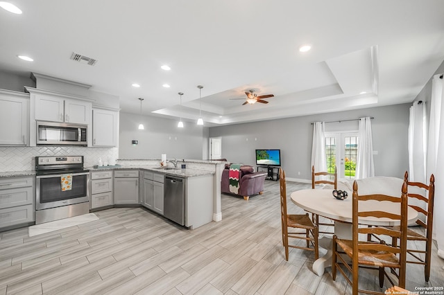 7186 Lake Placid, Corpus Christi, TX 78414 - kitchen with appliances with stainless steel finishes, gray cabinets, a peninsula, a tray ceiling, and visible vents