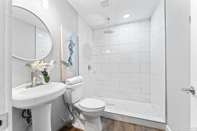 1851 Dawson St, San Antonio, TX 78202 - bathroom featuring wood finished floors, a tile shower, toilet, and a textured wall