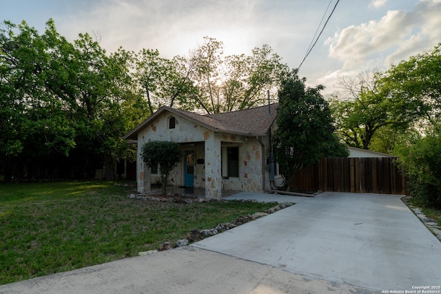 bungalow-style house with a porch, a front lawn, fence, and stone siding