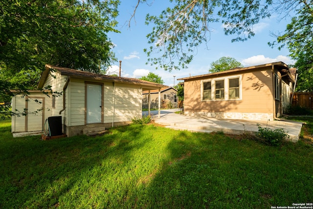 rear view of property with fence, an outbuilding, a yard, and a patio area