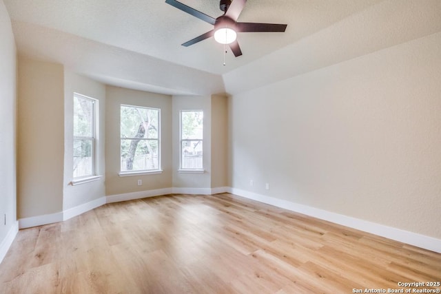 empty room featuring a ceiling fan, baseboards, and light wood-type flooring