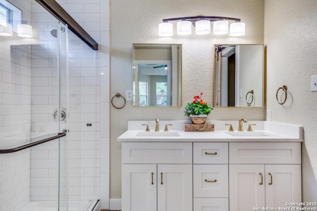 full bathroom featuring a sink, a textured wall, an enclosed shower, and double vanity