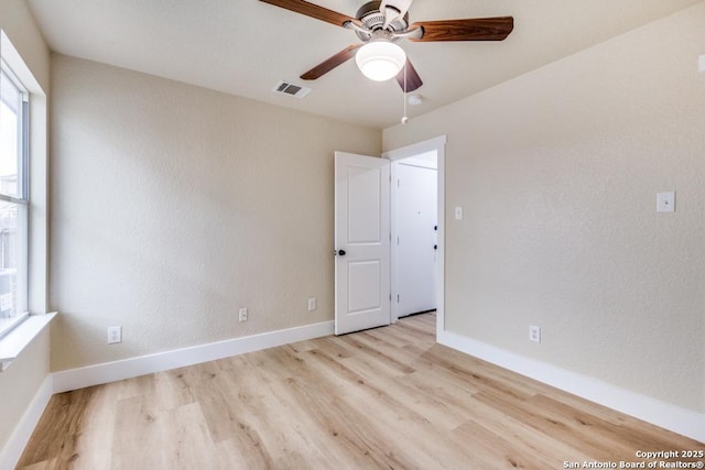 empty room featuring baseboards, ceiling fan, visible vents, and wood finished floors