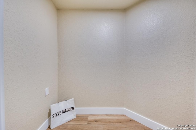 interior space with a textured wall, baseboards, and light wood-style flooring