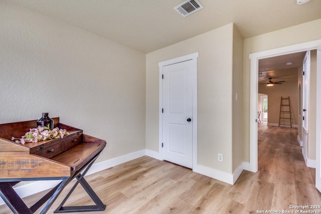 living area with baseboards, ceiling fan, light wood finished floors, and visible vents