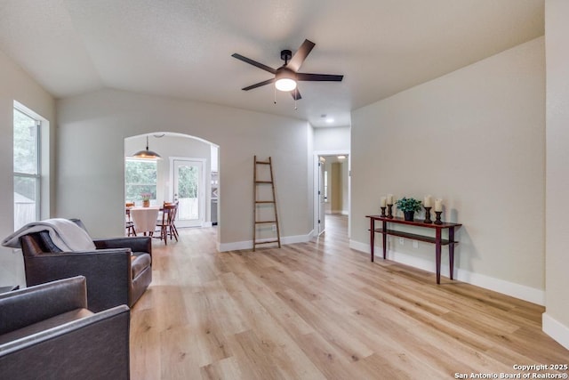 living area with arched walkways, a healthy amount of sunlight, and light wood-style floors
