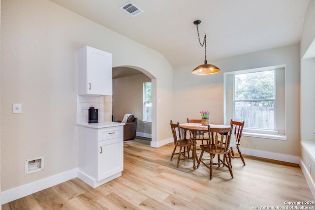 dining room with arched walkways, visible vents, plenty of natural light, and light wood-style flooring