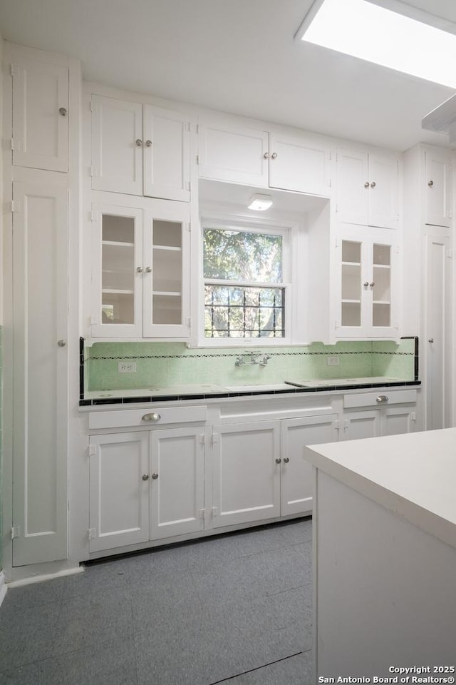kitchen featuring glass insert cabinets, light countertops, and white cabinets
