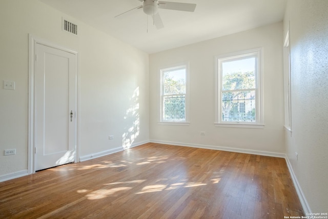 empty room featuring ceiling fan, visible vents, baseboards, and hardwood / wood-style flooring