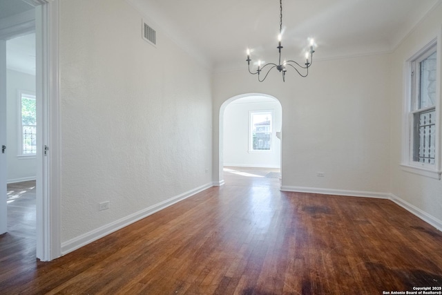 unfurnished dining area with an inviting chandelier, visible vents, baseboards, dark wood-style floors, and arched walkways