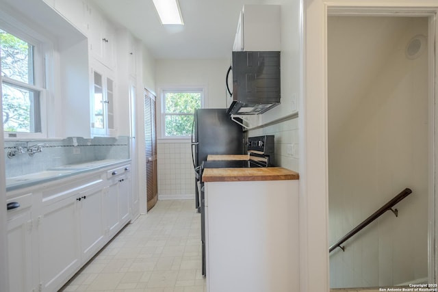 kitchen featuring decorative backsplash, white cabinetry, range, and wooden counters