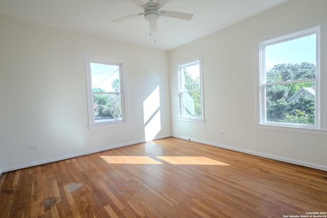 spare room featuring light wood-style floors, a ceiling fan, and baseboards