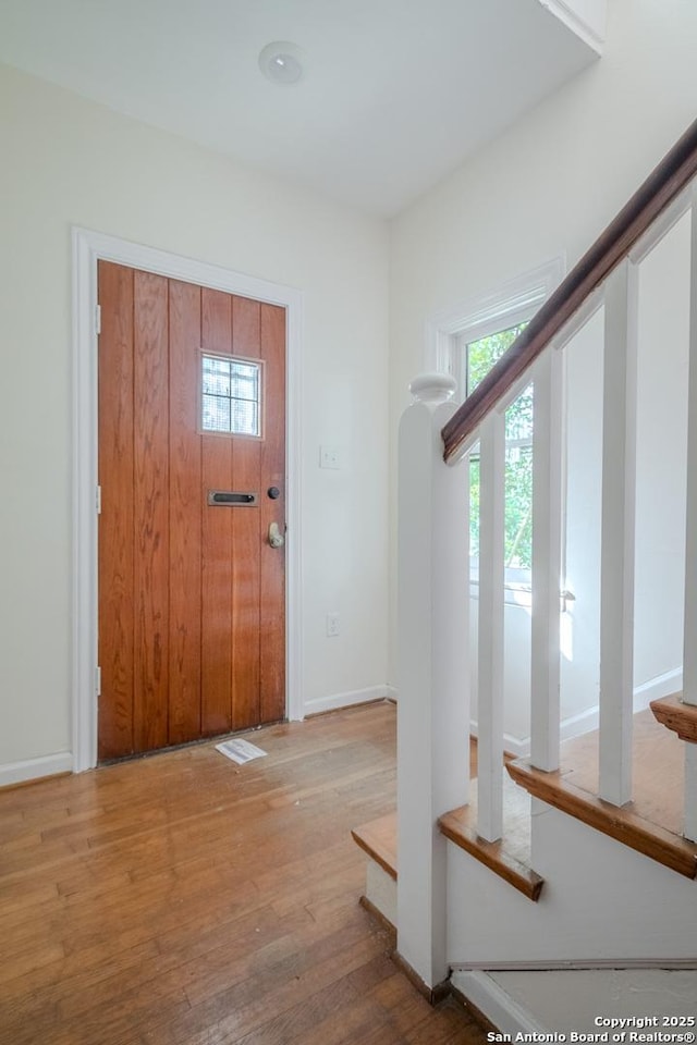 foyer entrance featuring baseboards, a healthy amount of sunlight, and wood finished floors