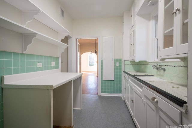 kitchen with visible vents, glass insert cabinets, tile walls, light countertops, and white cabinetry