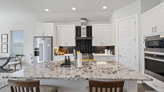 29919 Capstone Walk, Boerne, TX 78015 - kitchen featuring wall chimney range hood, stainless steel appliances, white cabinetry, and a kitchen bar