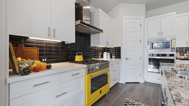 29919 Capstone Walk, Boerne, TX 78015 - kitchen with dark wood-style flooring, wall chimney exhaust hood, stainless steel appliances, white cabinetry, and tasteful backsplash