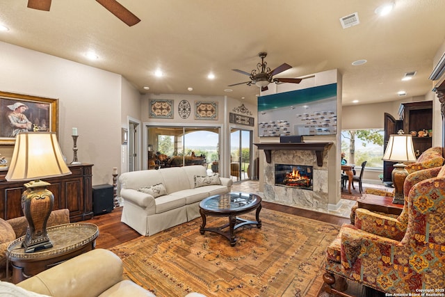 living room featuring visible vents, a ceiling fan, wood finished floors, and a premium fireplace
