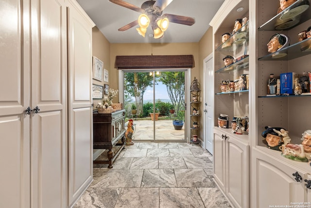 doorway featuring a ceiling fan and stone tile flooring