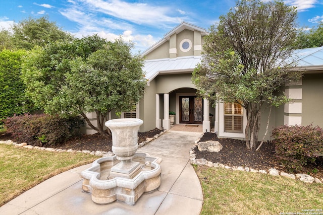 view of exterior entry with a standing seam roof, french doors, metal roof, and stucco siding