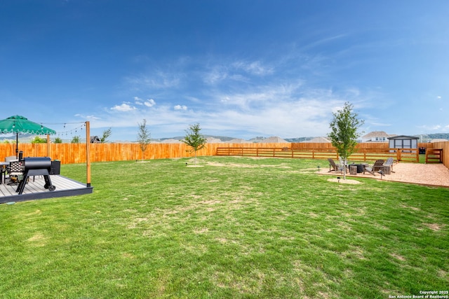view of yard featuring a fenced backyard and a deck with mountain view