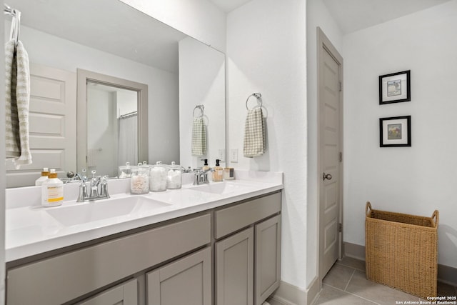 full bathroom featuring double vanity, baseboards, a sink, and tile patterned flooring