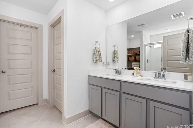 full bath featuring a sink, tile patterned flooring, a shower stall, and double vanity