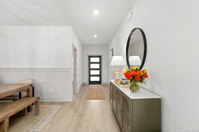 entrance foyer featuring recessed lighting, light wood finished floors, a decorative wall, and a wainscoted wall