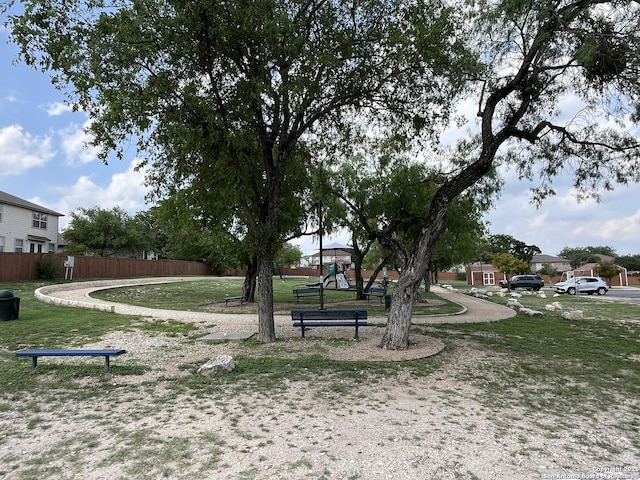view of home's community featuring a lawn, fence, and playground community