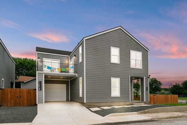 traditional-style home with an attached garage, fence, a balcony, and concrete driveway