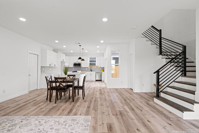 dining space with recessed lighting, light wood finished floors, and stairway