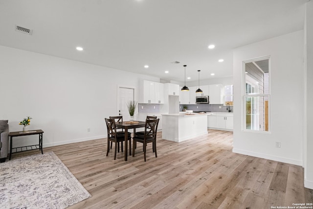 dining room featuring recessed lighting, baseboards, visible vents, and light wood finished floors