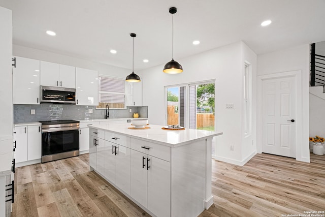 kitchen featuring light wood-style floors, a sink, appliances with stainless steel finishes, and white cabinets