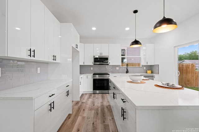 kitchen featuring light wood-style floors, modern cabinets, white cabinetry, tasteful backsplash, and stainless steel appliances