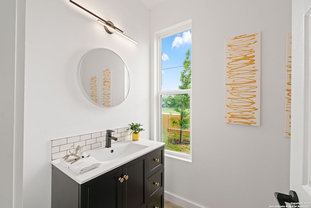 bathroom with vanity, baseboards, a wealth of natural light, and tasteful backsplash