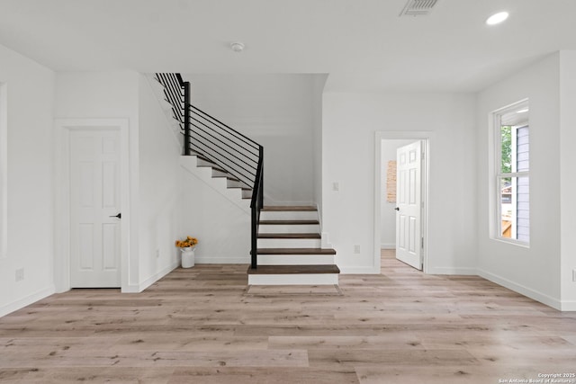 foyer with baseboards, wood finished floors, and stairway